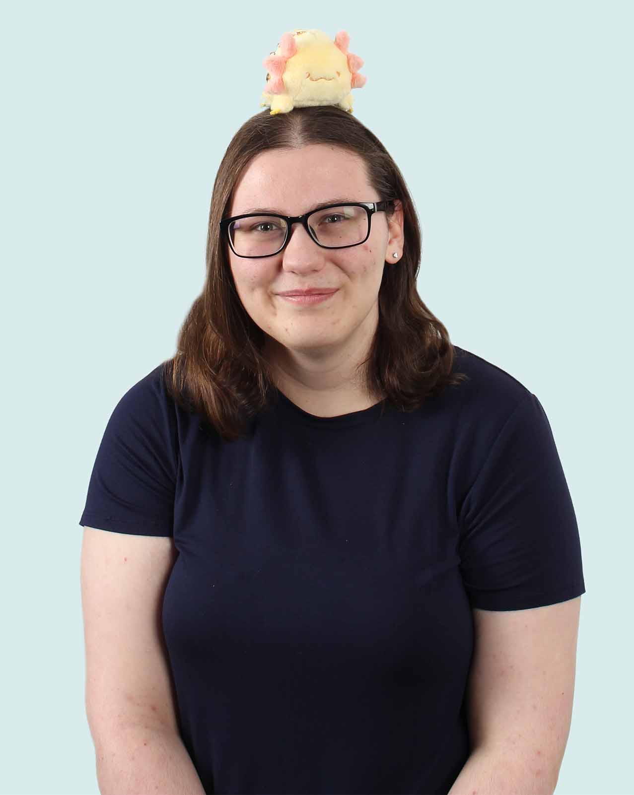 Image of Emily, a girl with brown hair and glasses, with an axolotl stuffy on her head