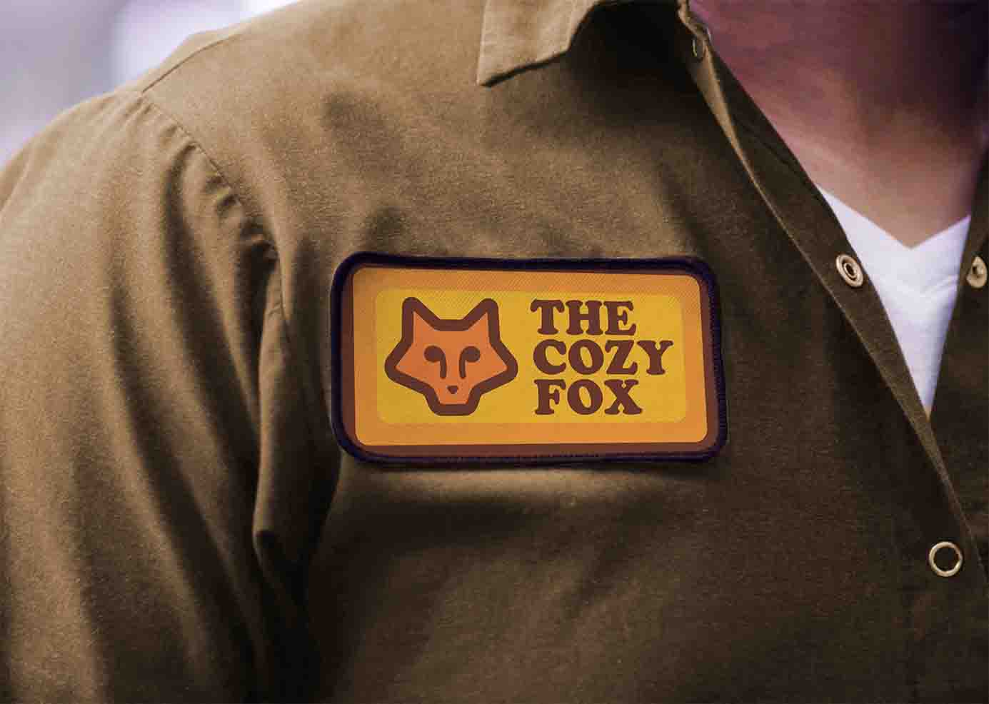 The Cozy Fox logo on a patch on a brown shirt